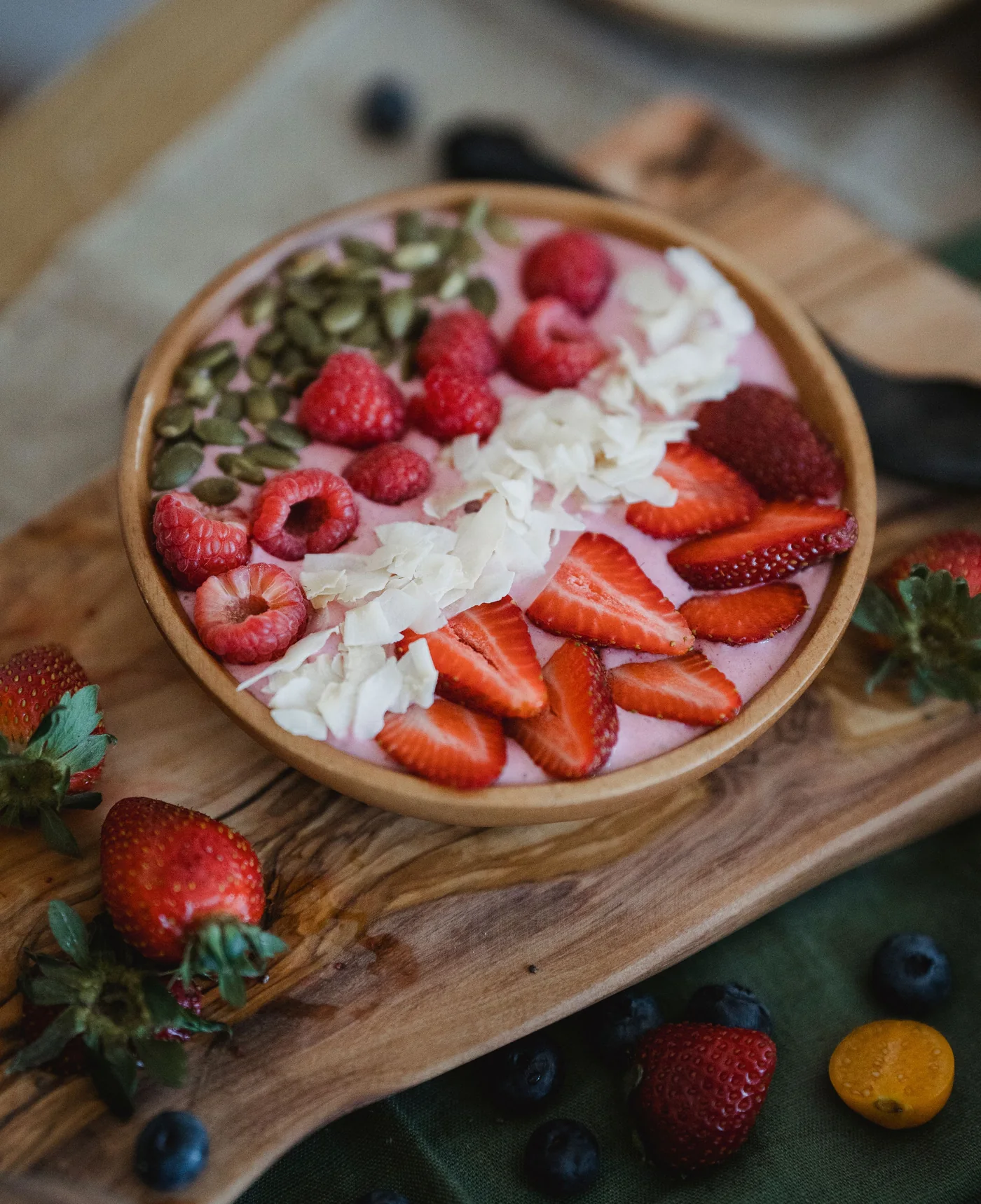 Smoothie bowl topped with strawberries, raspberries, coconut flakes and pumpkin seeds