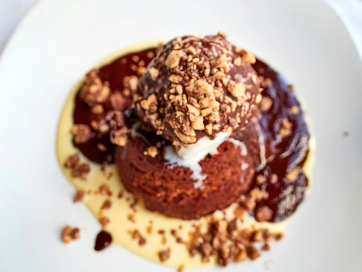 Sticky toffee pudding with a crumble-style topping in a pool of custard and toffee sauce