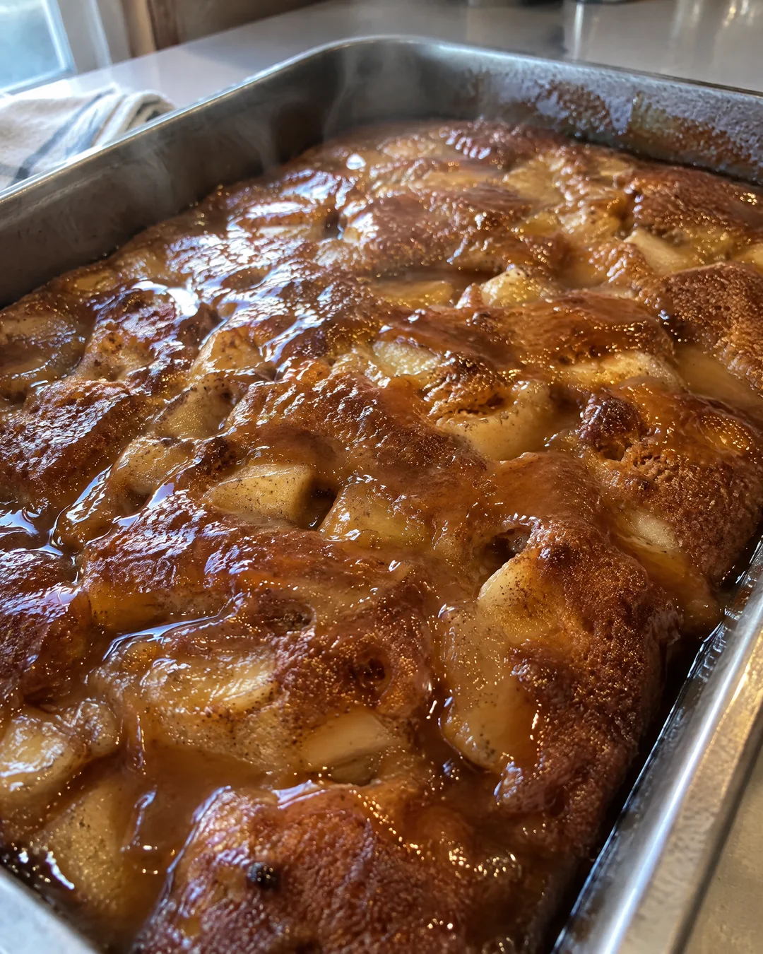 Hot brown sugar caramel glaze soaking into apple dapple cake in its pan