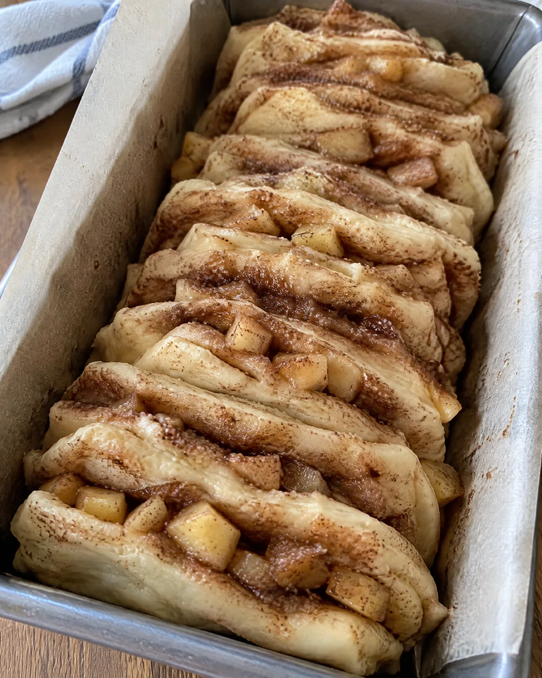 Stacked dough squares standing in a loaf pan
