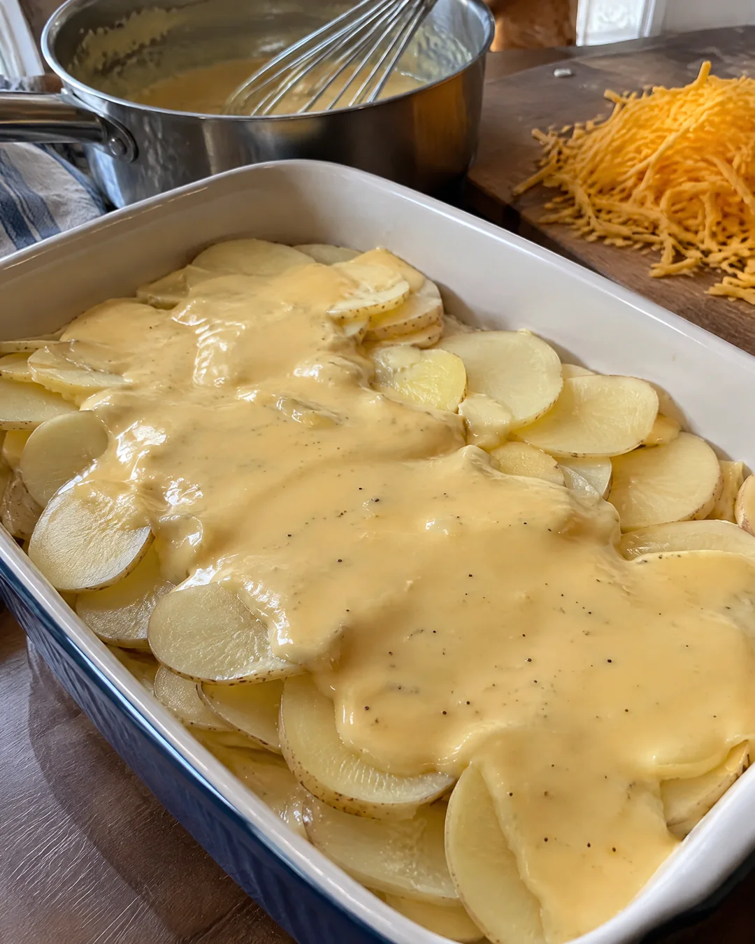 Layering thin potato slices with cheddar cheese sauce
