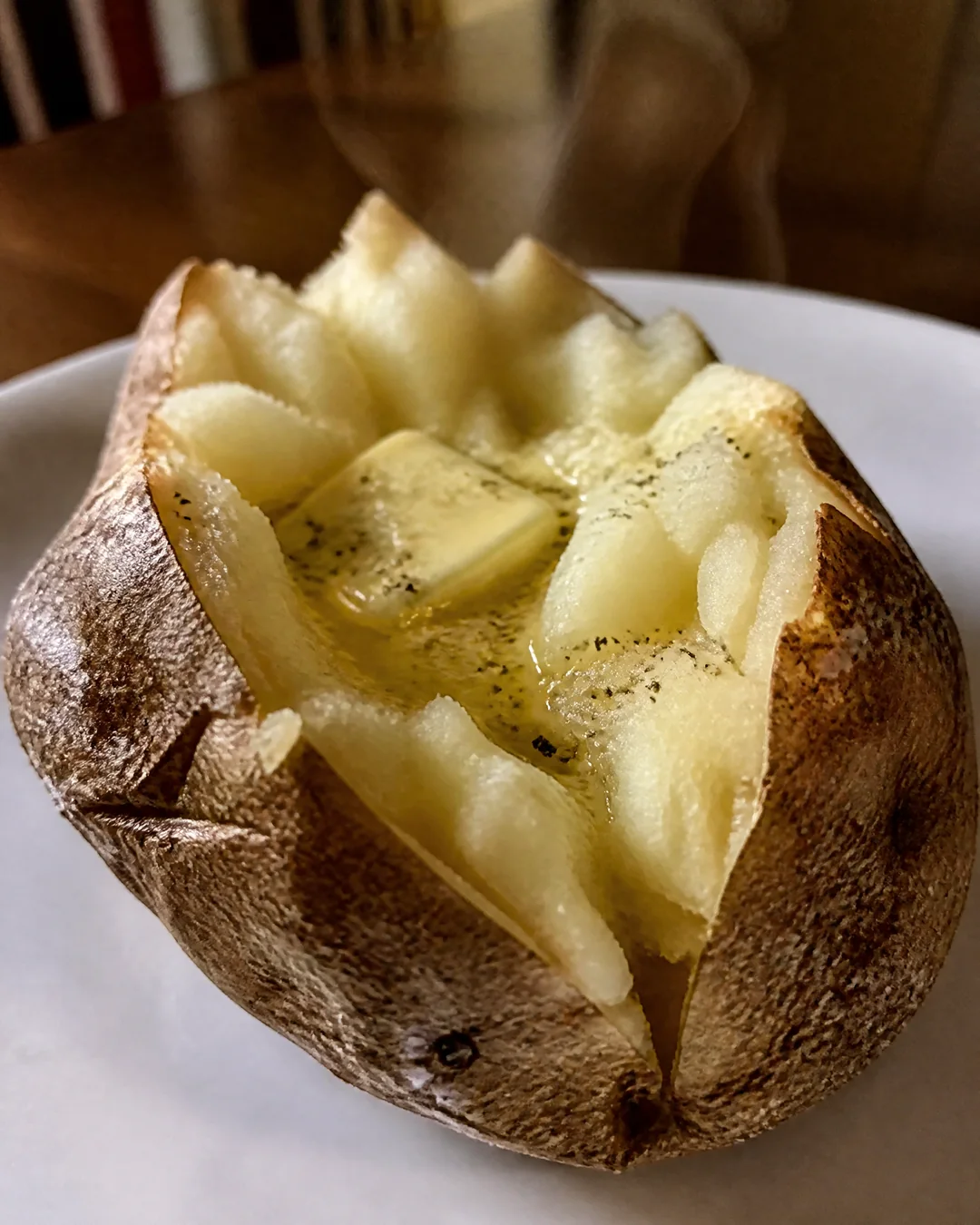 A baked potato split open with fluffy white insides and a melting pat of butter