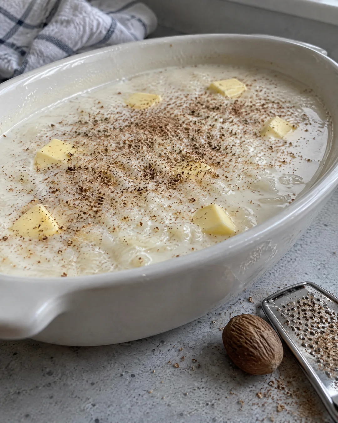 Rice and milk in a buttered baking dish with nutmeg grated over the top