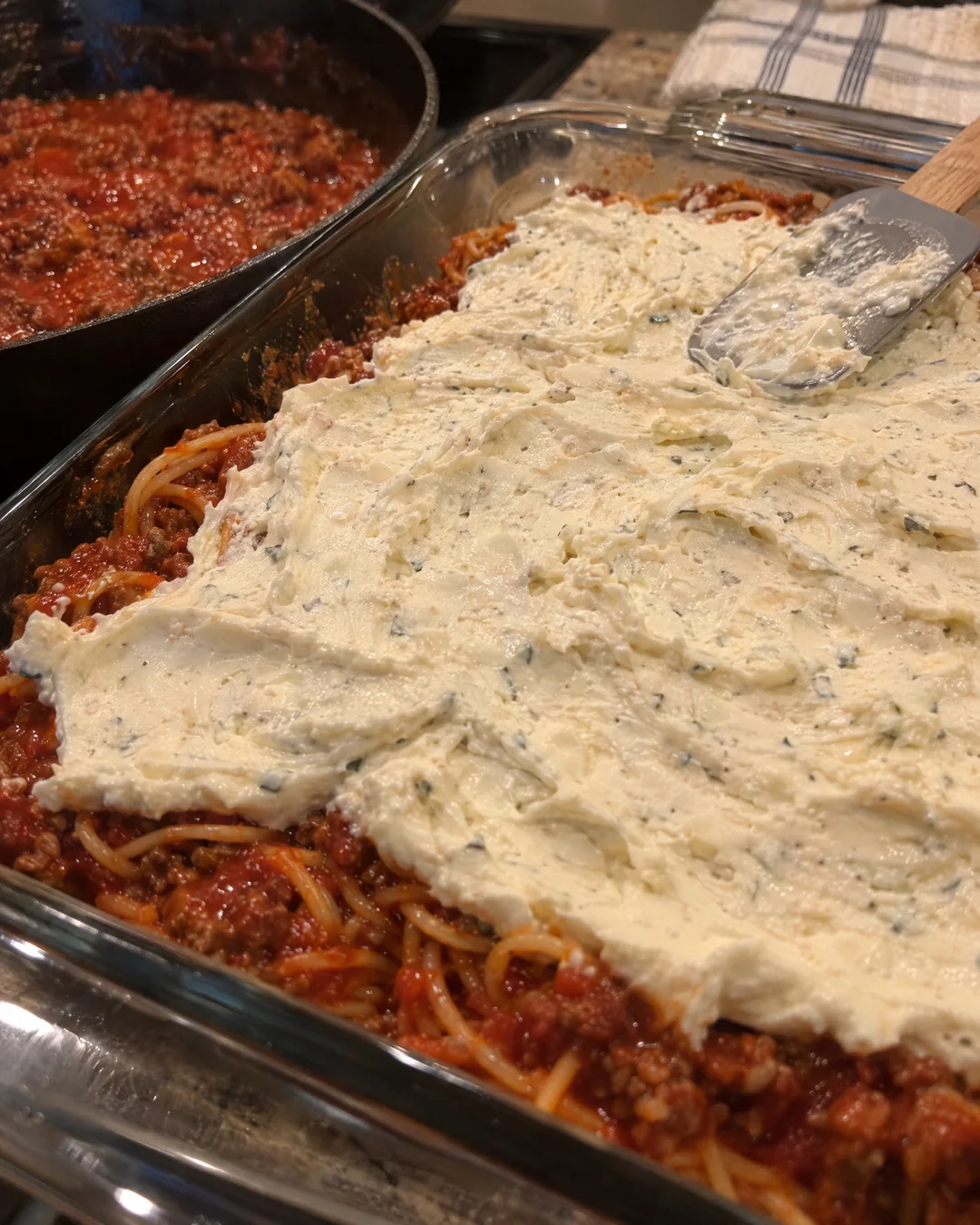 Spaghetti layered in a baking dish with the creamy cream cheese layer spread on top
