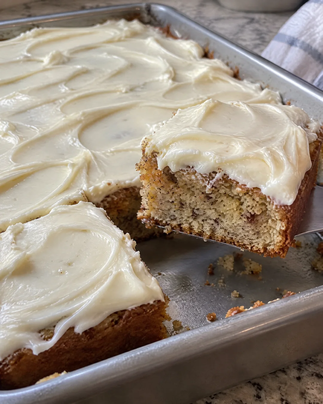 Banana cake in the pan spread with thick cream cheese frosting