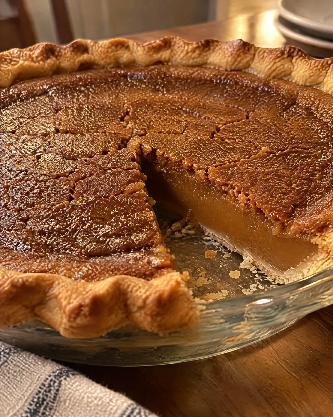 Whole baked brown sugar pie with a crackly golden top in a glass pie plate