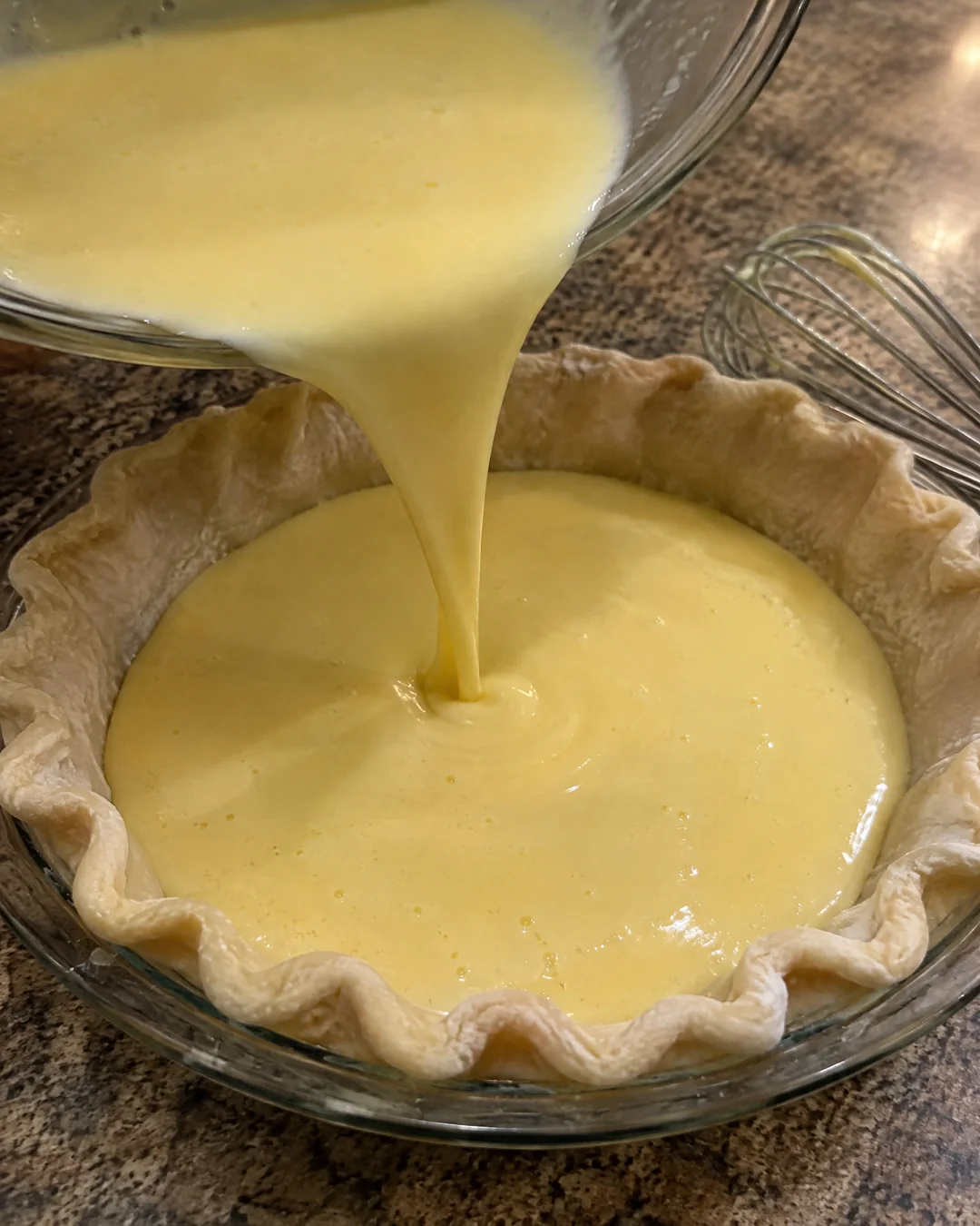 Pouring the thin buttermilk custard filling into an unbaked pie crust