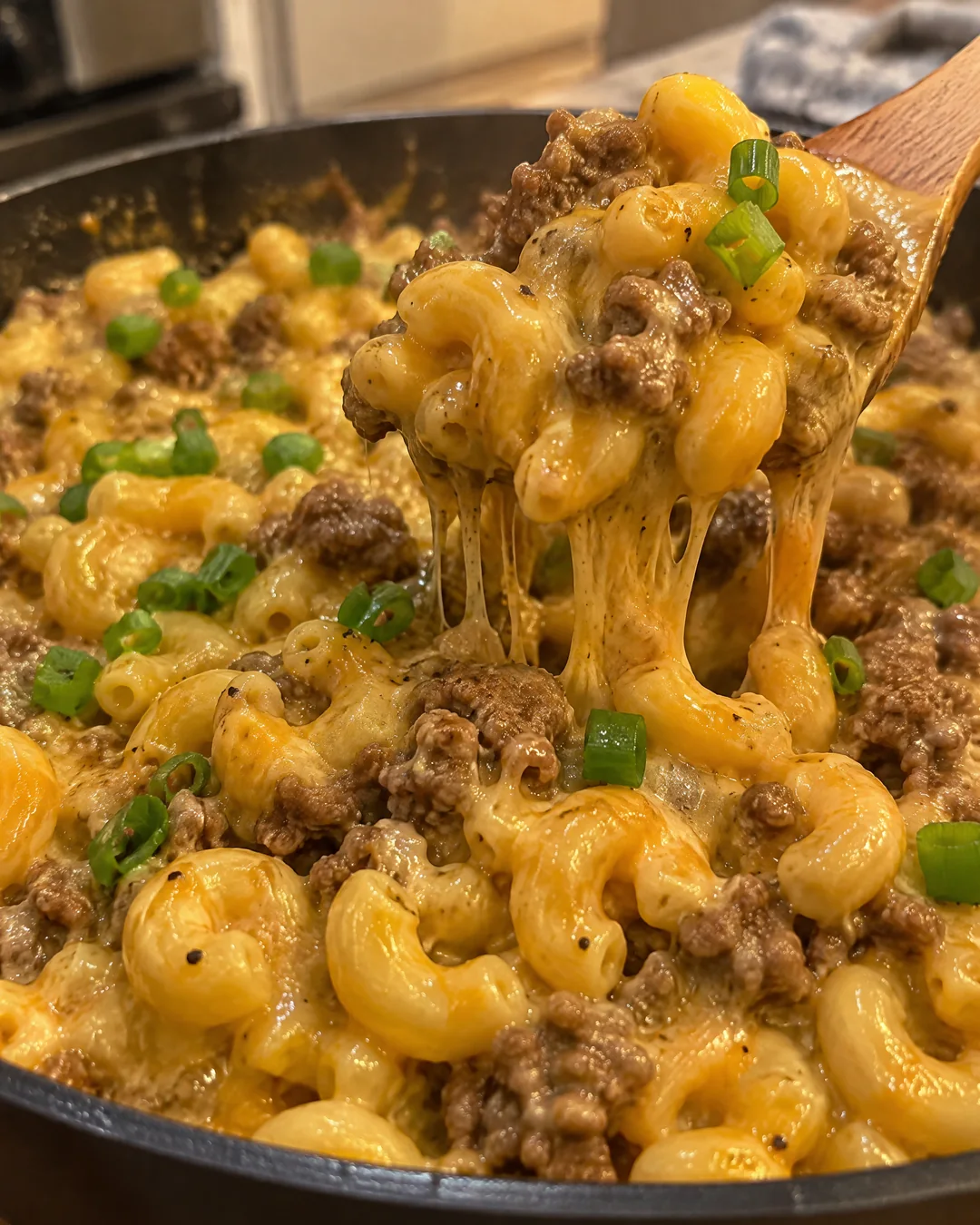 Creamy cheeseburger macaroni in a skillet with melted cheddar and green onion