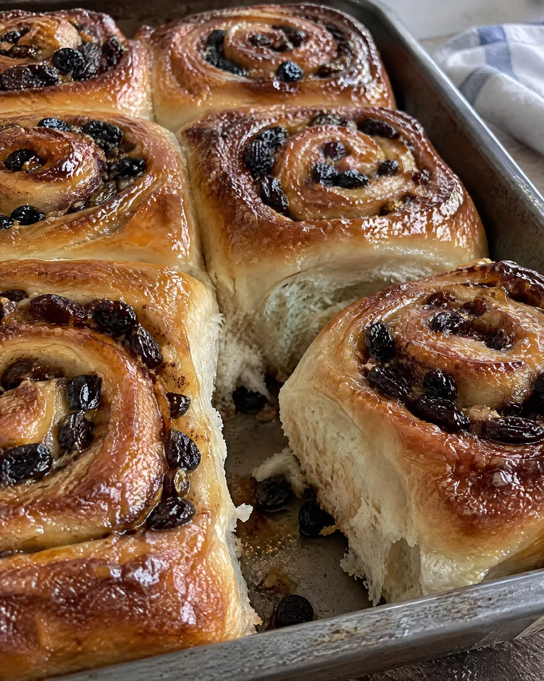 Sticky glazed Chelsea buns baked together in a pan