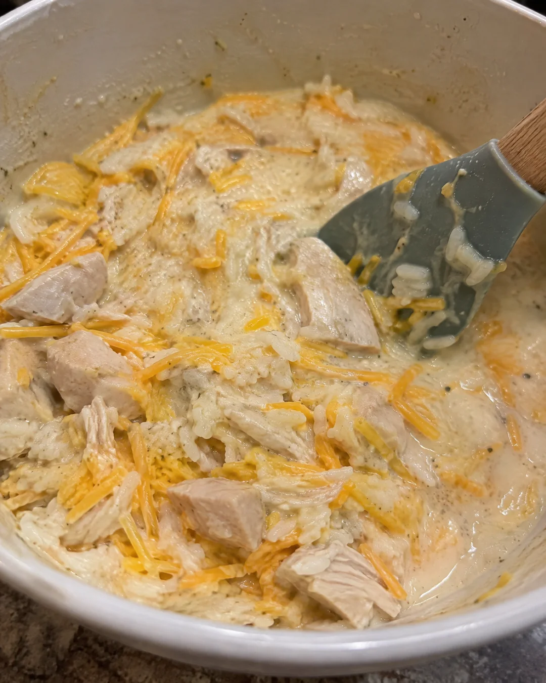 Stirring chicken, rice, cream soups and cheddar together in a large bowl