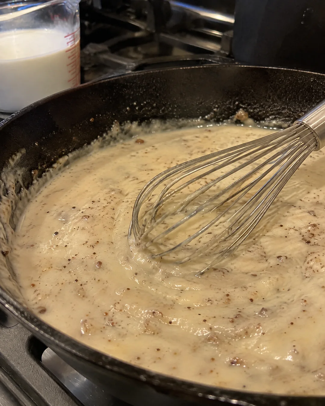 White pepper gravy being whisked in the cast iron skillet after frying the steaks