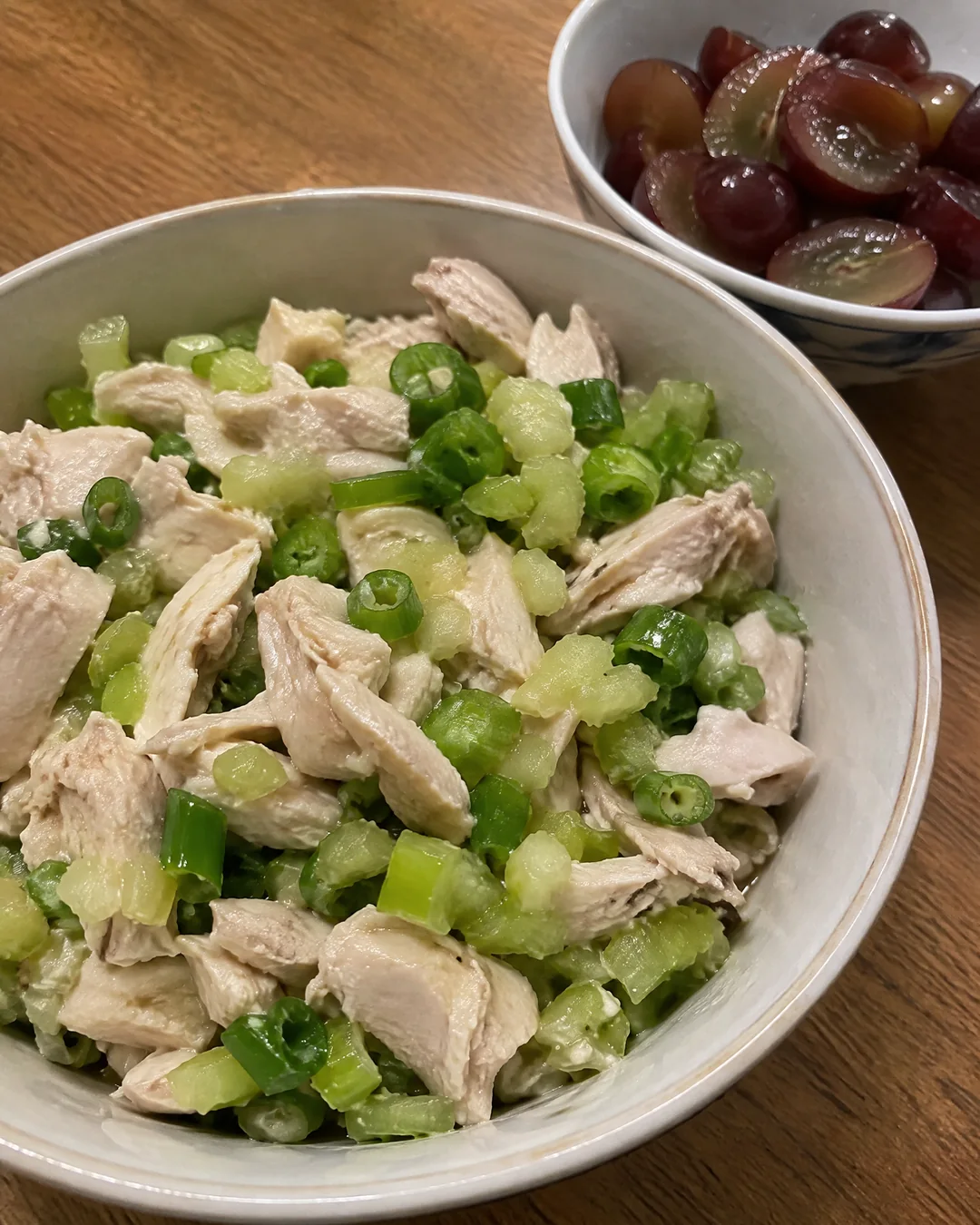 Chopped poached chicken, celery and green onion in a bowl before the dressing