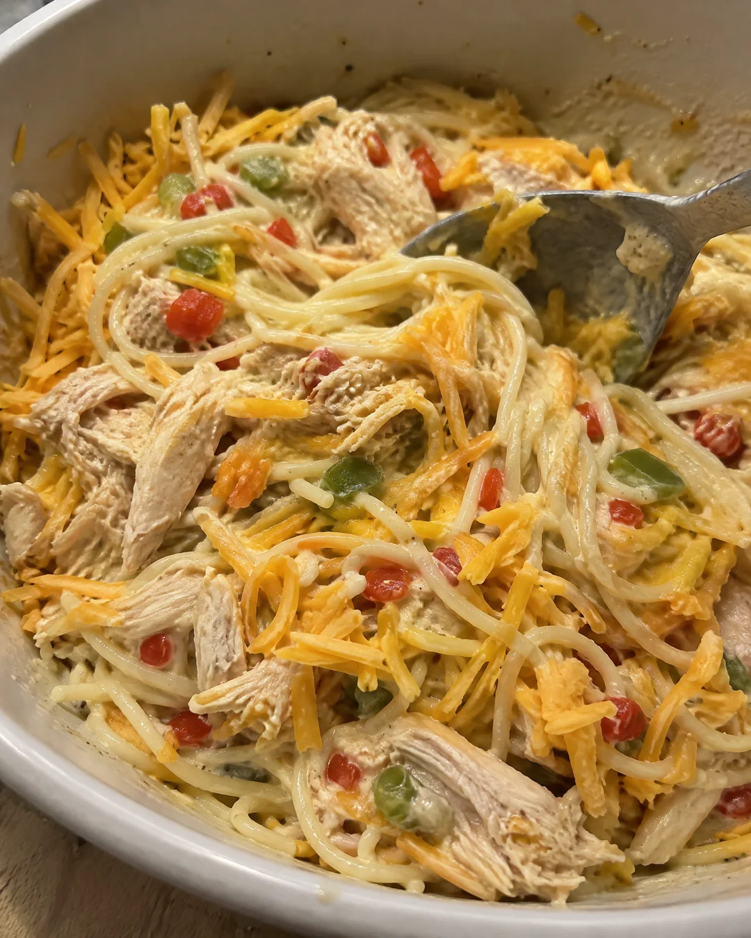 Spaghetti, pulled chicken and the creamy sauce being folded together in a large bowl