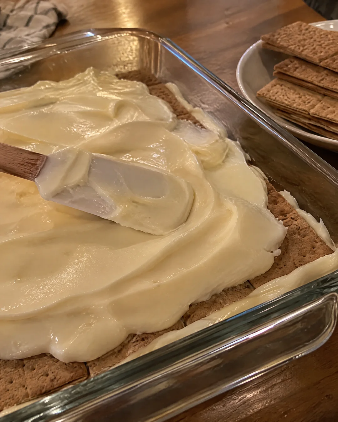 Layers of graham crackers and vanilla cream in a glass dish