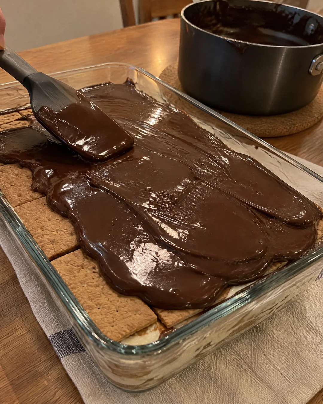 Shiny chocolate glaze poured over no-bake eclair cake