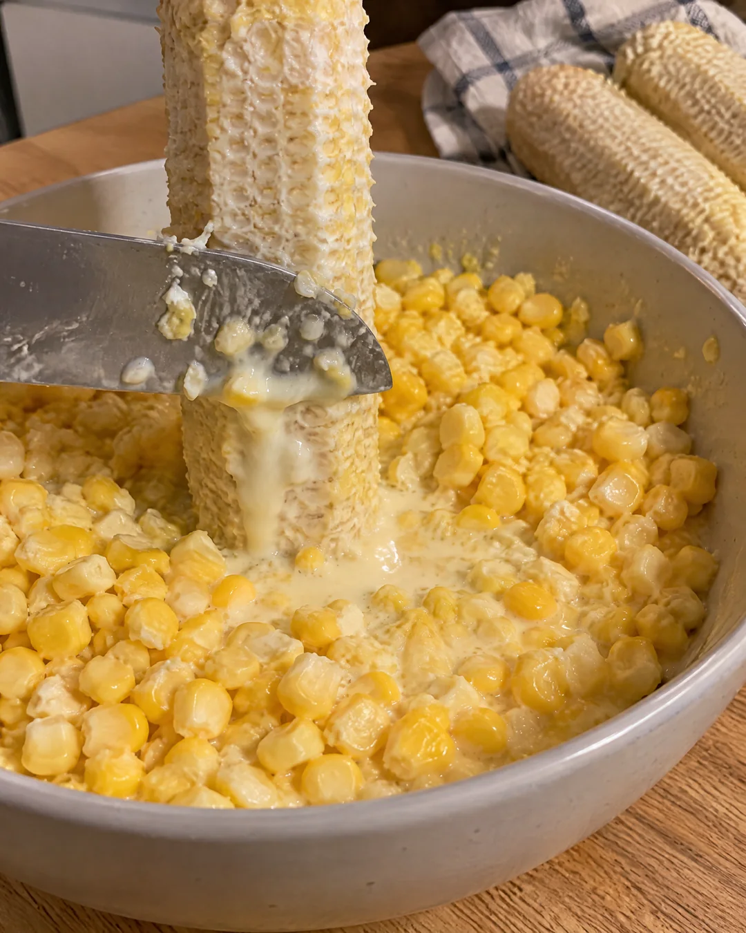 Scraping the milky pulp from a corn cob with the back of a knife