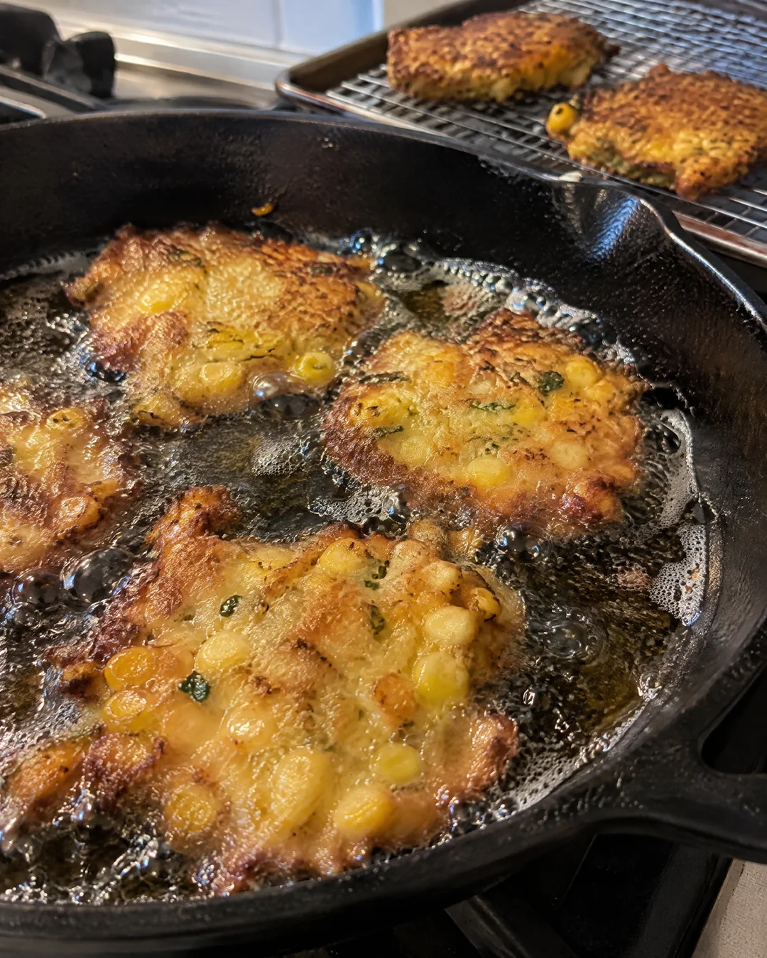Corn fritters frying in a cast iron skillet