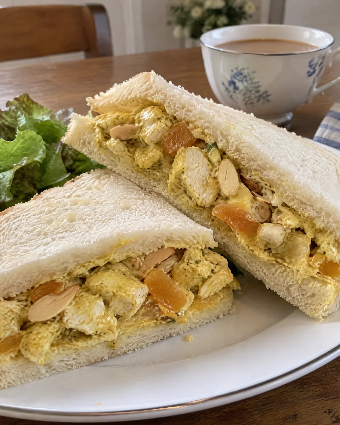 Coronation chicken sandwiches on a plate with tea