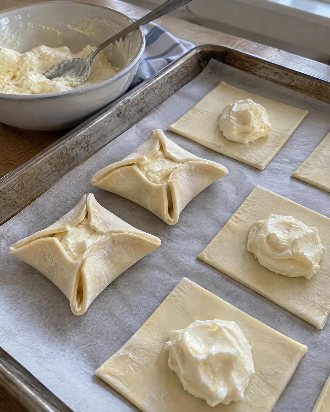 Cream cheese filling spooned onto puff pastry squares