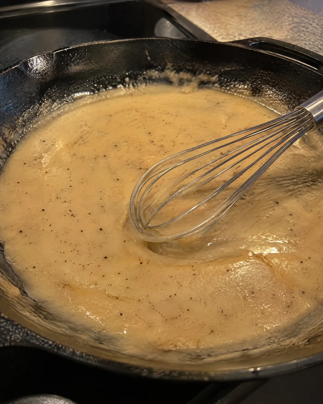 Toasted flour and chicken drippings cooking in a cast iron skillet before the milk goes in