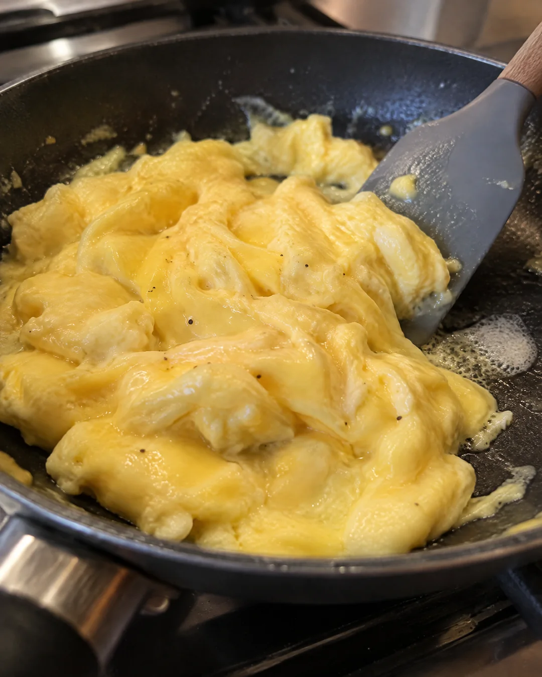 Soft scrambled eggs forming big glossy folds in a skillet