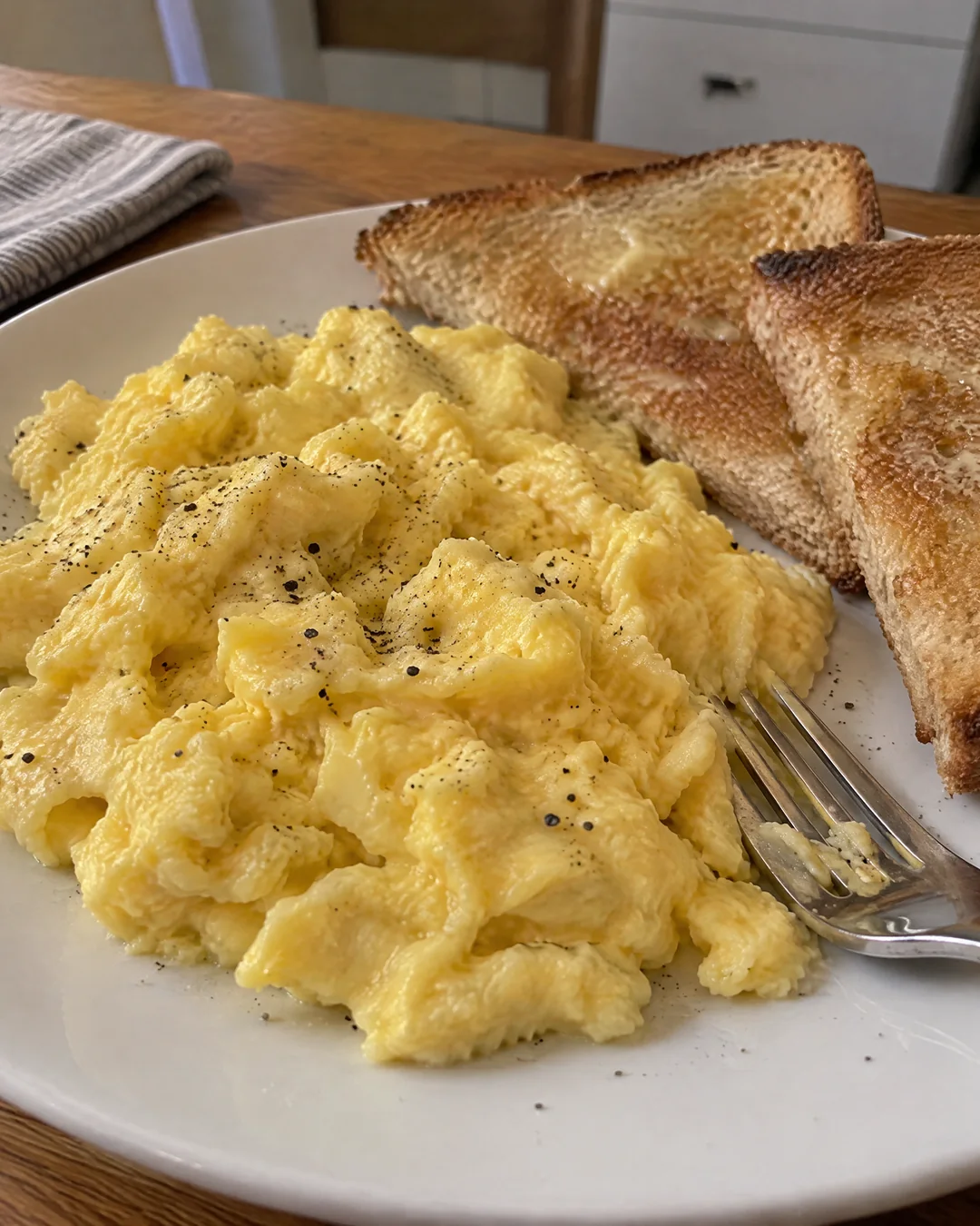 Creamy scrambled eggs on a plate with buttered toast