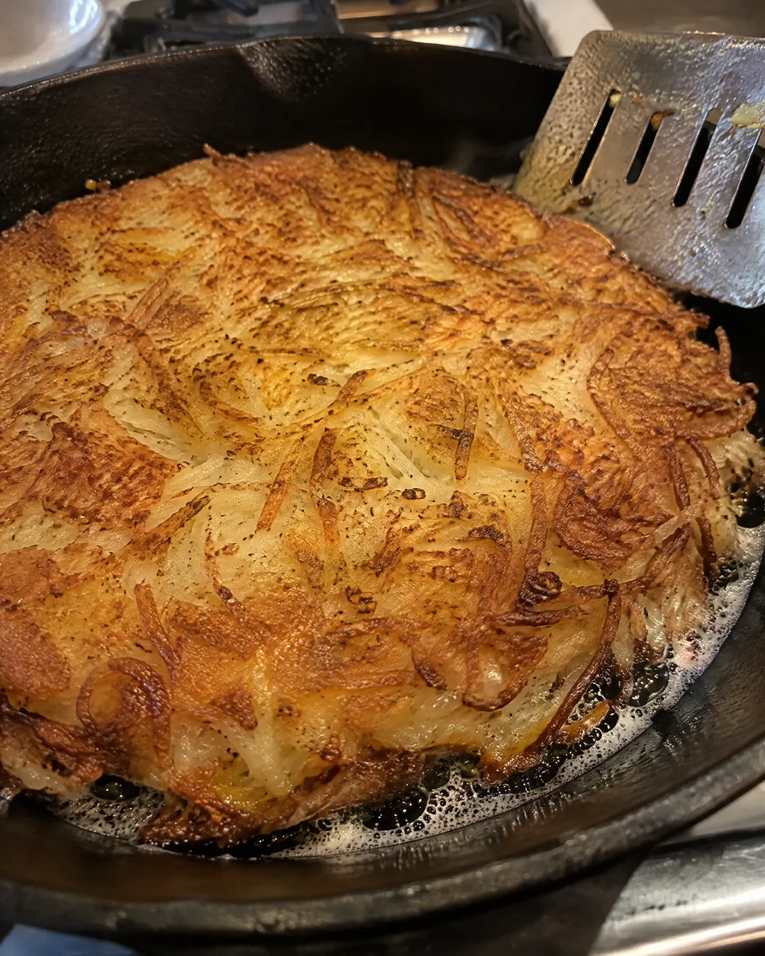 Hash browns in a cast iron skillet, deep golden brown after the flip