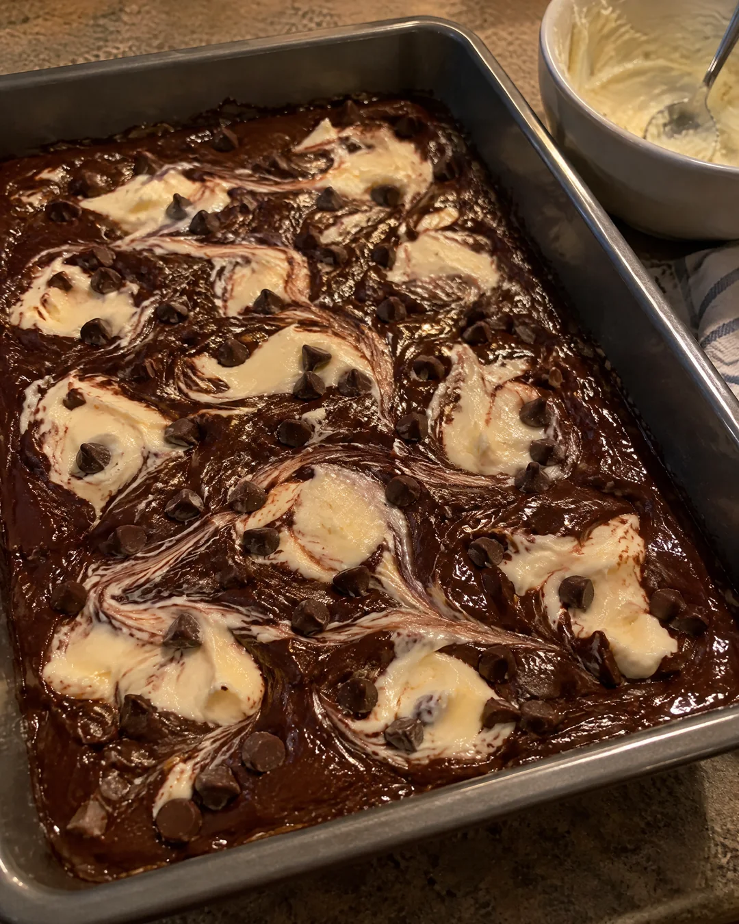 Spoonfuls of cream cheese dropped over chocolate cake batter