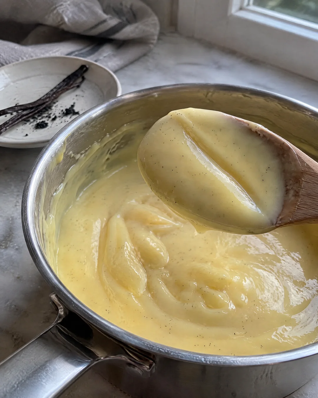 Thick homemade custard being stirred in a saucepan for trifle