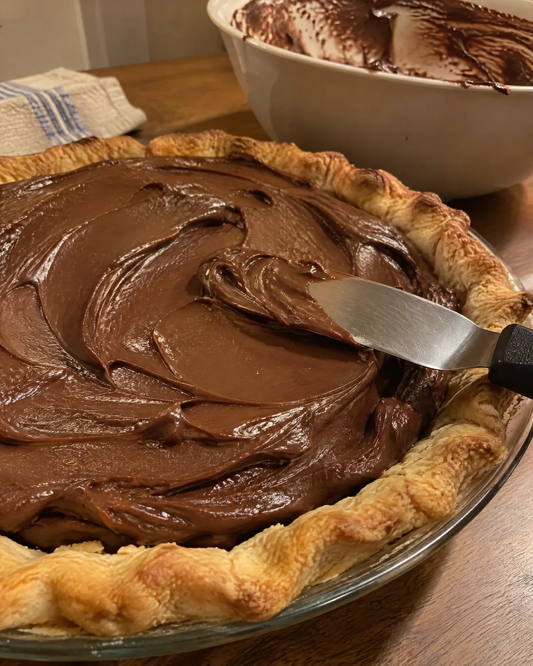 Silky chocolate filling being spread into a baked pie crust