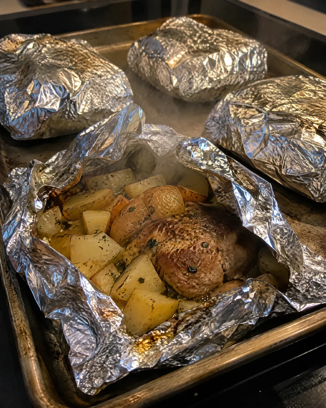 Sealed foil packets on a baking sheet