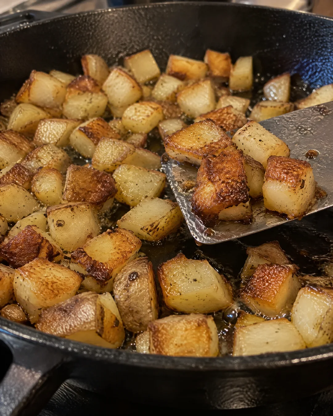 Diced potatoes browning undisturbed in a cast iron skillet