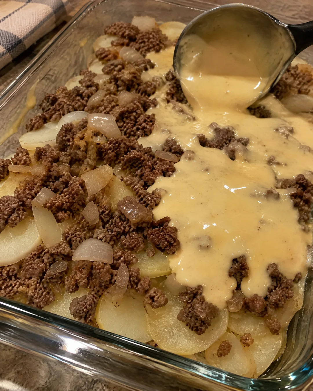 Layering thin potato slices and browned ground beef in a baking dish
