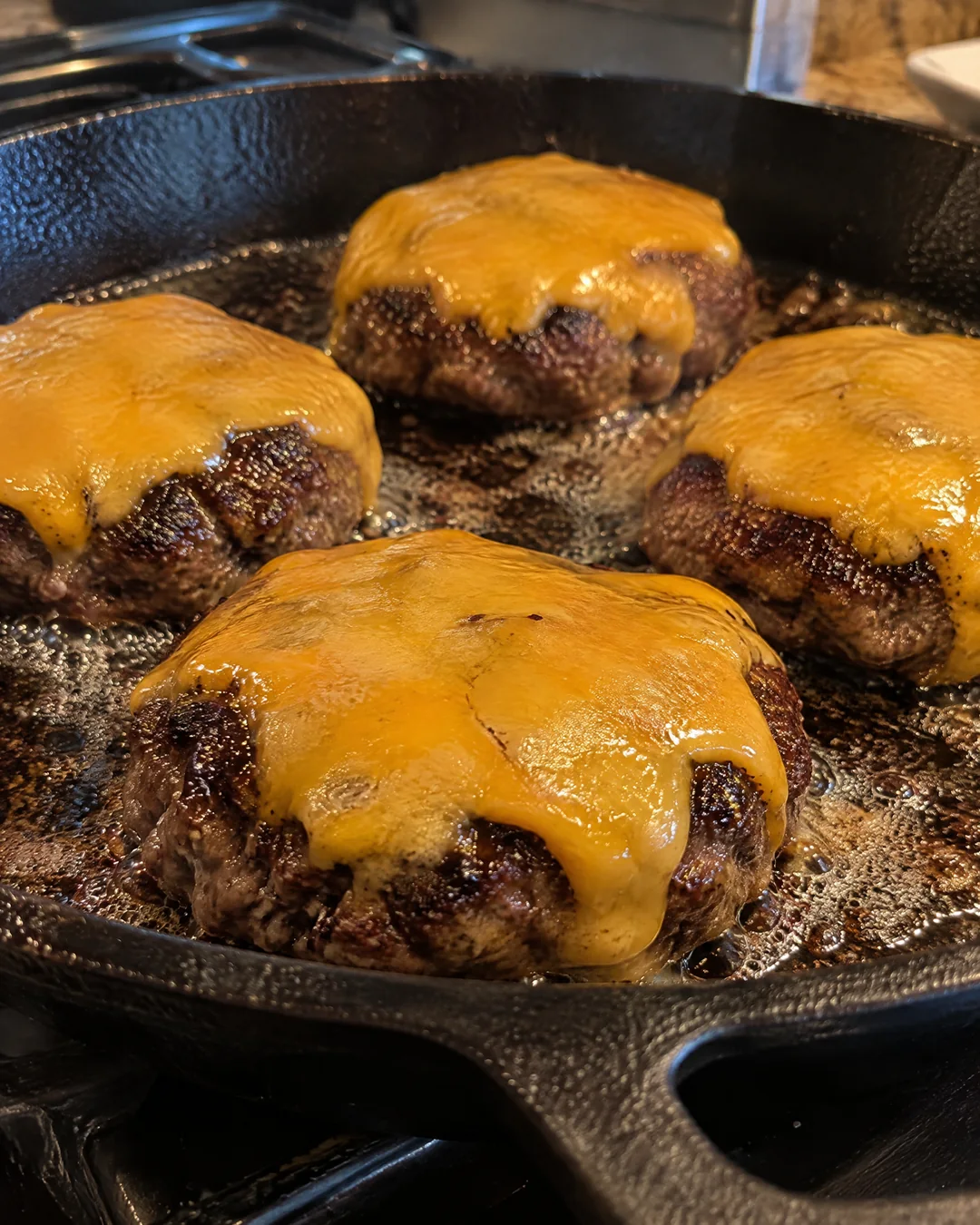 Hamburgers with melted cheddar in a cast iron skillet