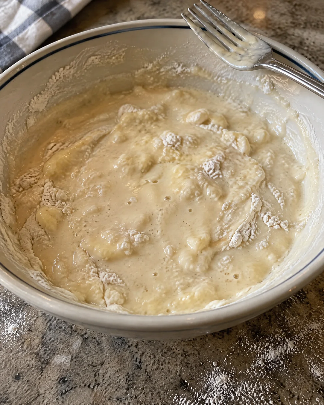 Lumpy homemade pancake batter in a bowl with a fork, rested and slightly puffed