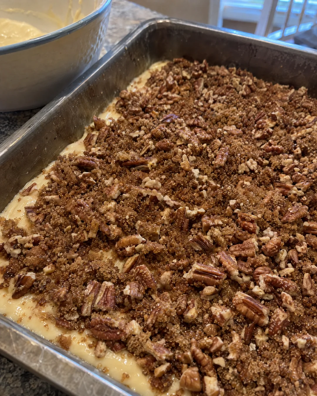 Brown sugar and cinnamon swirl scattered over honey bun cake batter in a 9x13 pan
