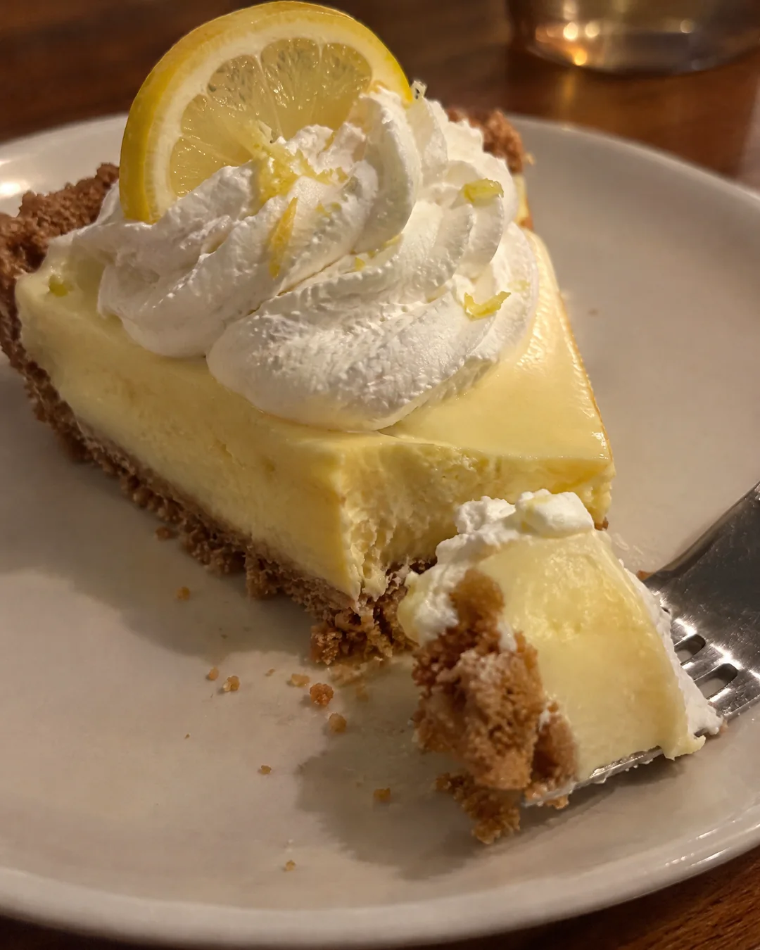 A slice of lemon icebox pie with whipped cream on a graham cracker crust