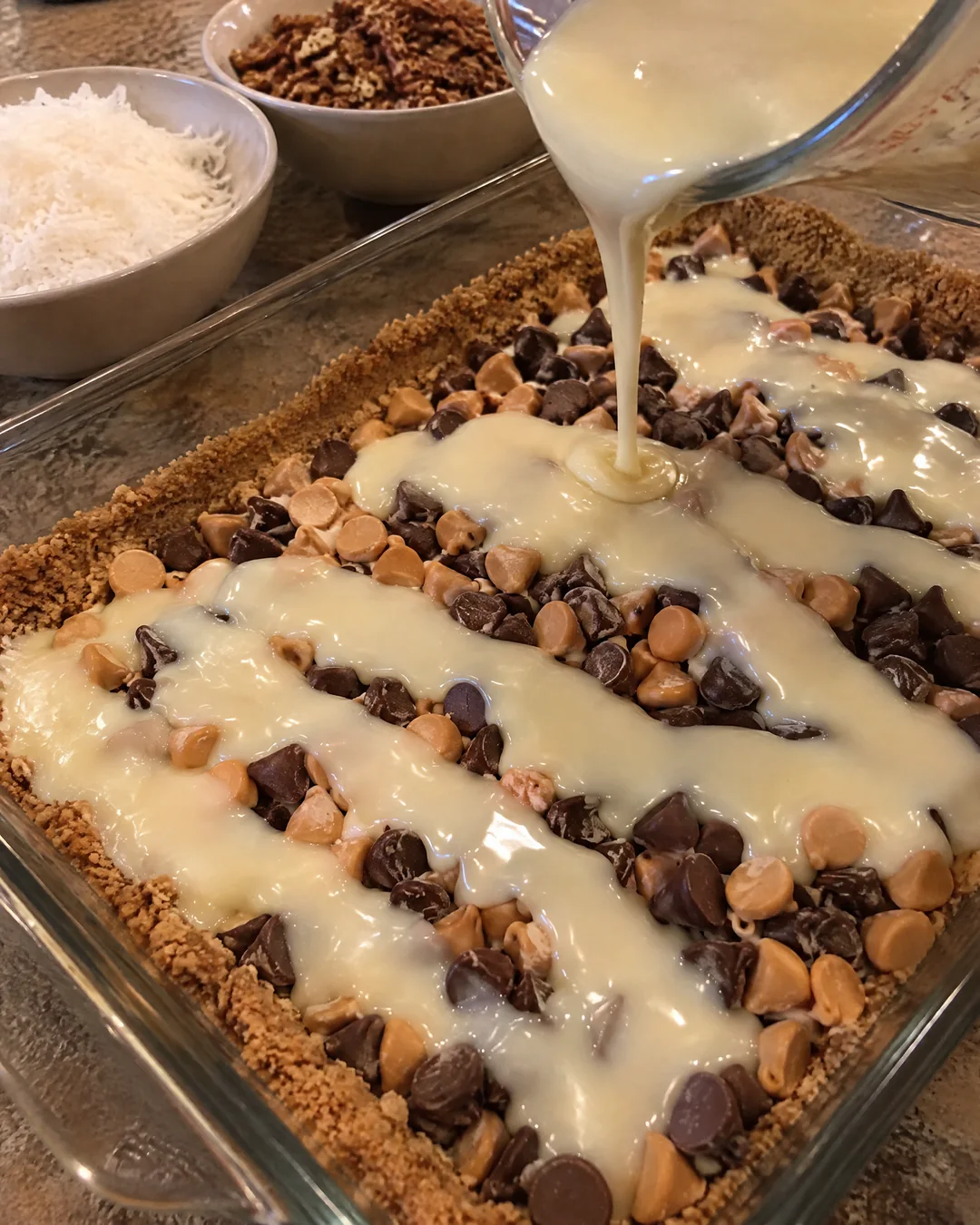 Sweetened condensed milk poured over chips for magic cookie bars