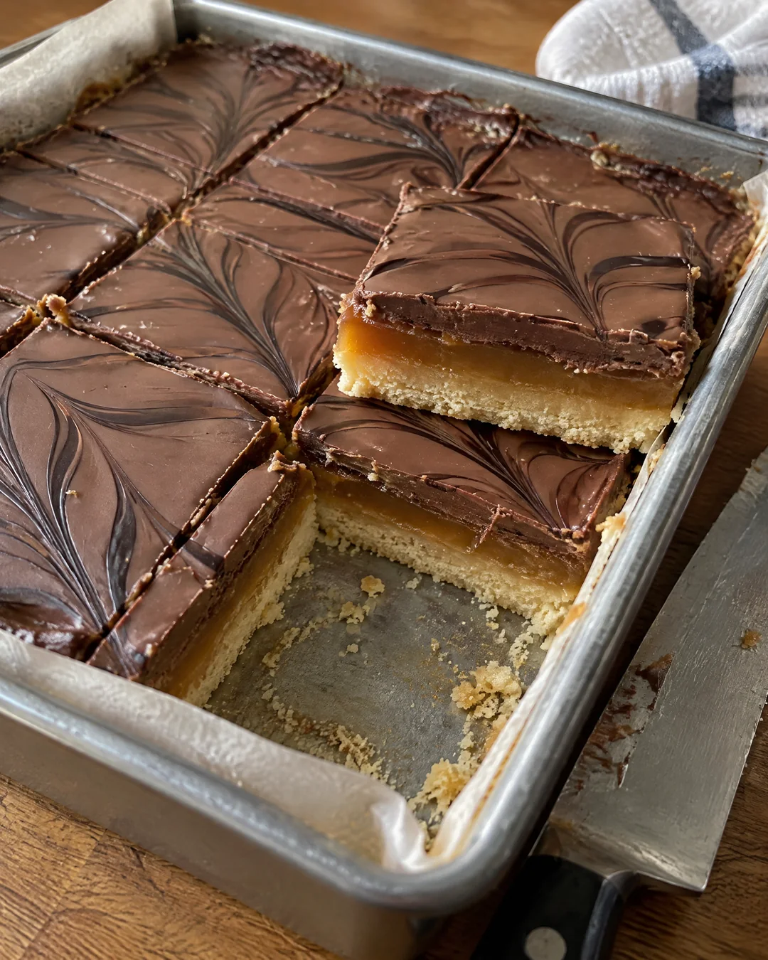 Millionaire's shortbread in its pan, chocolate set, the first squares cut