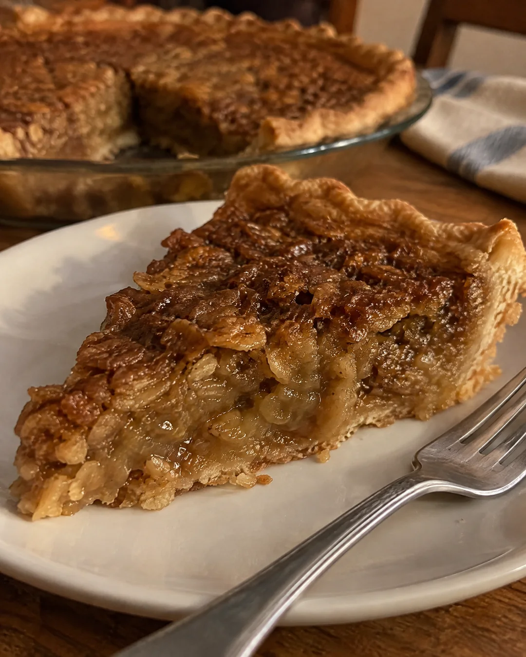 A wedge of oatmeal pie on a plate, the crackled caramel top over a dense gooey chewy filling