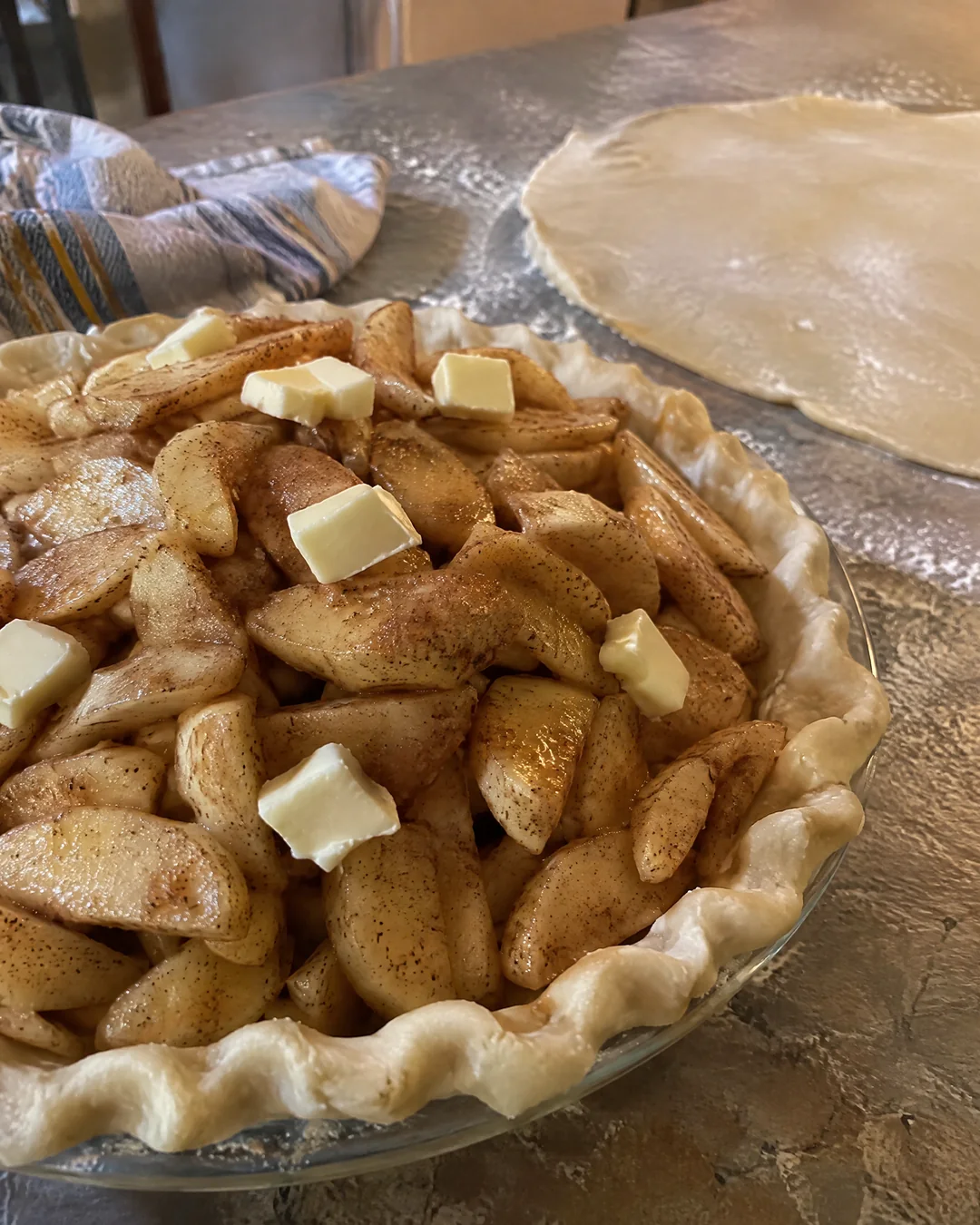 Sliced apples tossed with sugar and cinnamon piled high in an unbaked pie crust