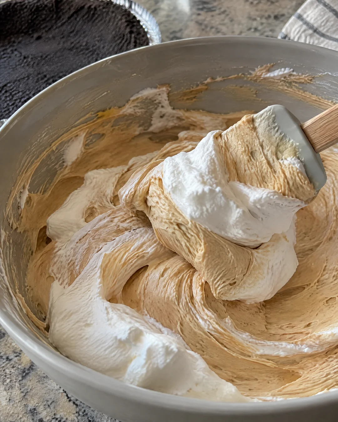 Whipped cream being folded into peanut butter filling in a mixing bowl