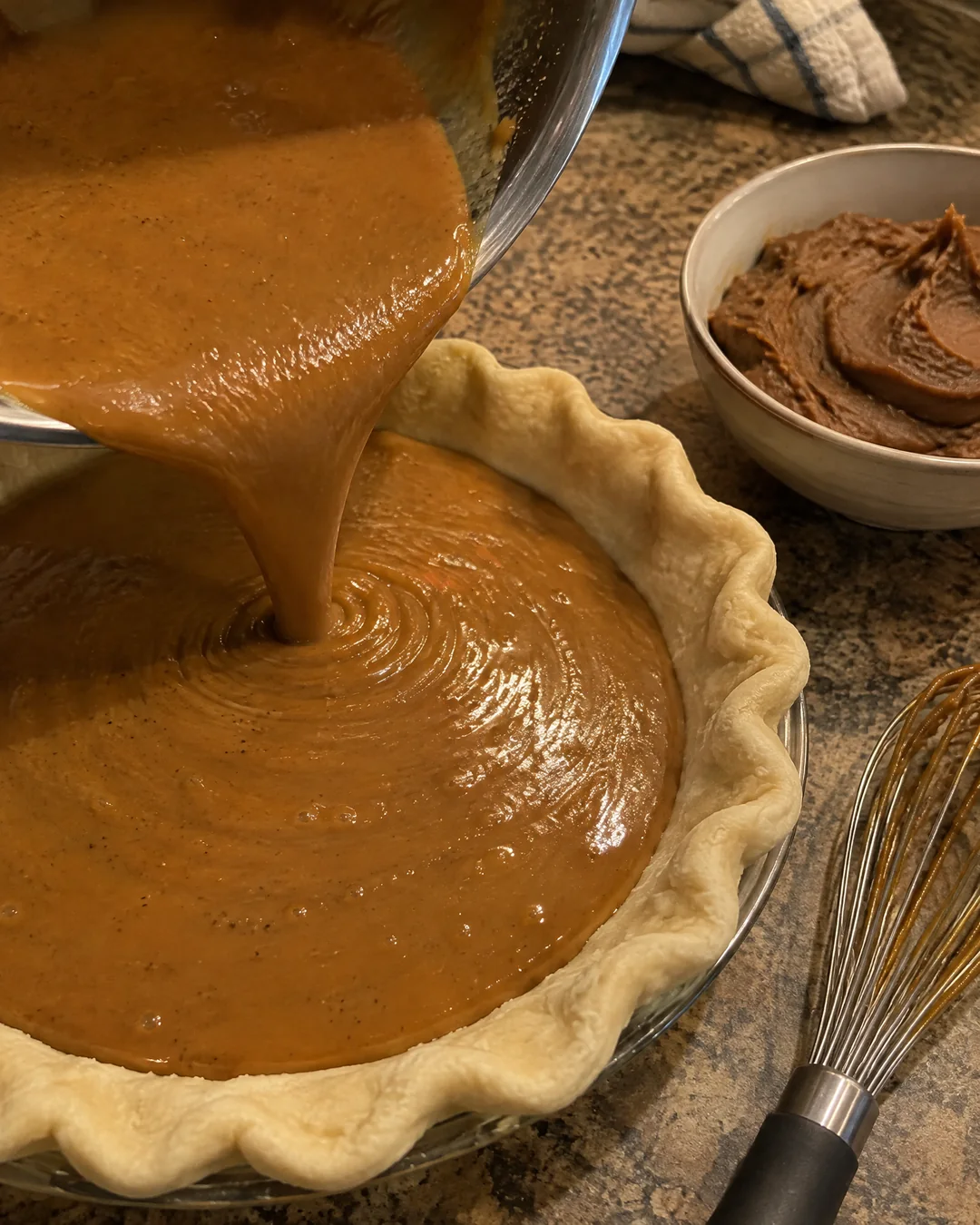 Smooth caramel-colored pinto bean pie filling being poured into an unbaked crimped pie crust