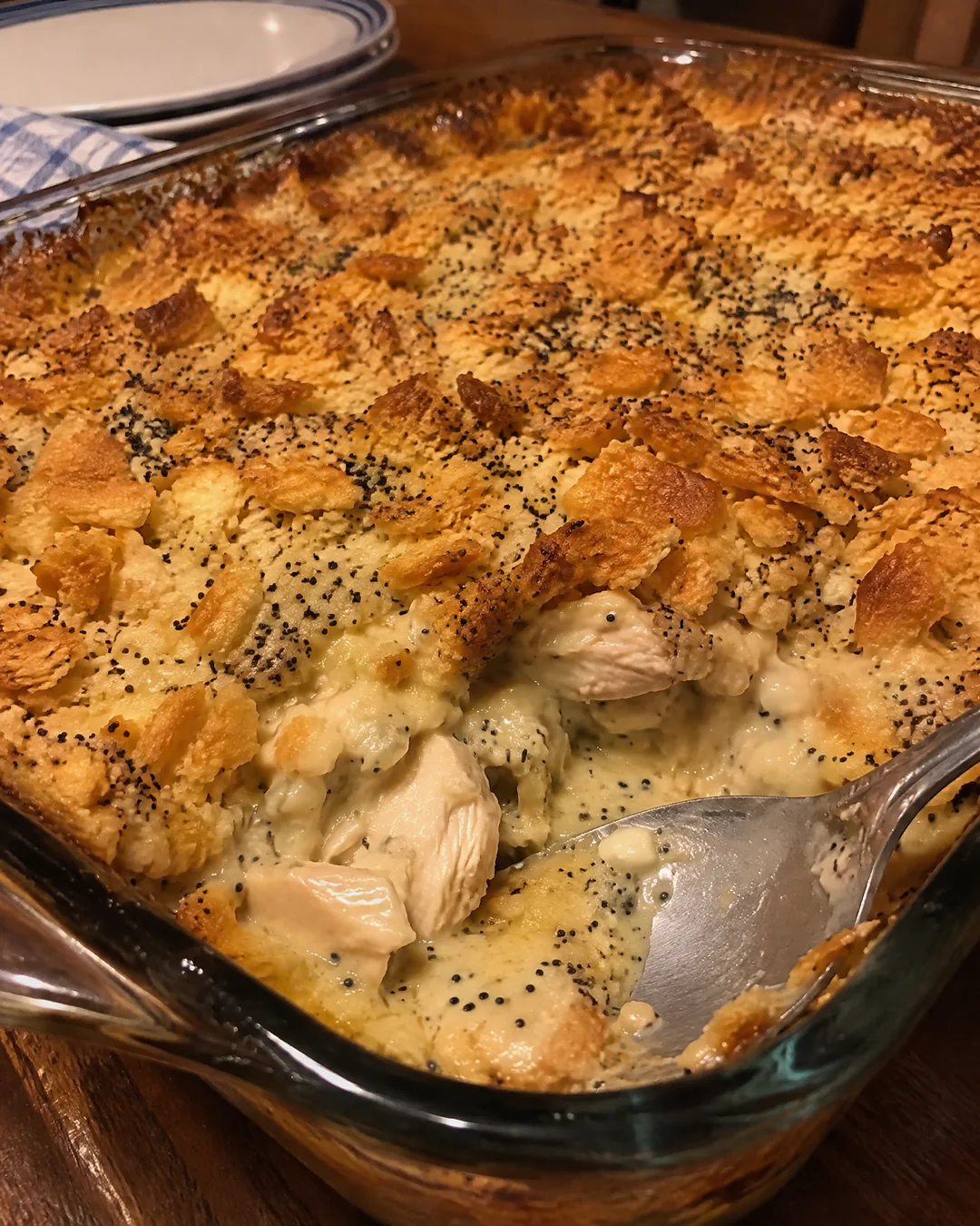 Baked poppy seed chicken casserole in a glass dish with one corner scooped out