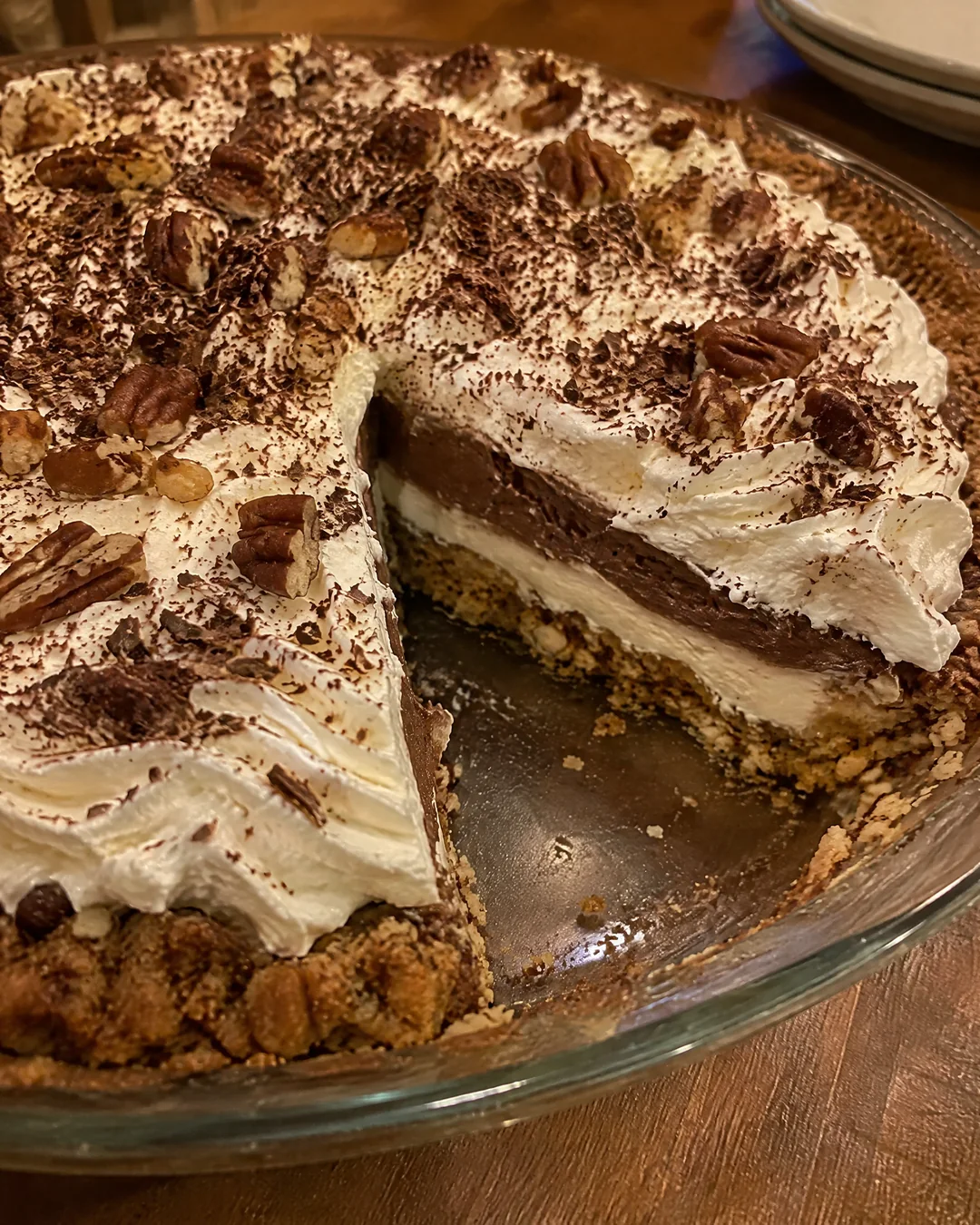 A whole possum pie seen from above with one slice removed, showing the four layers