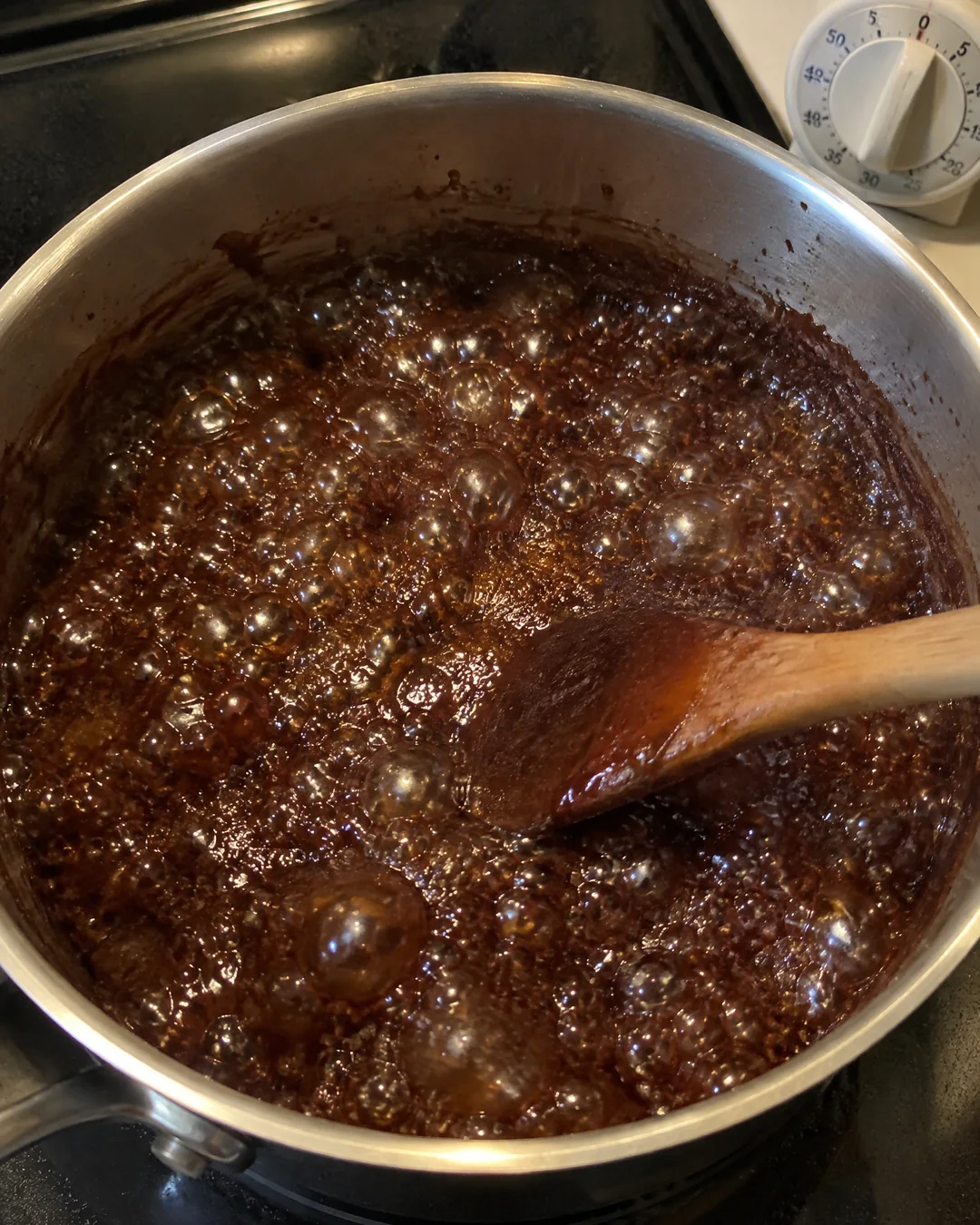 Chocolate mixture at a full rolling boil in a saucepan with a timer beside it