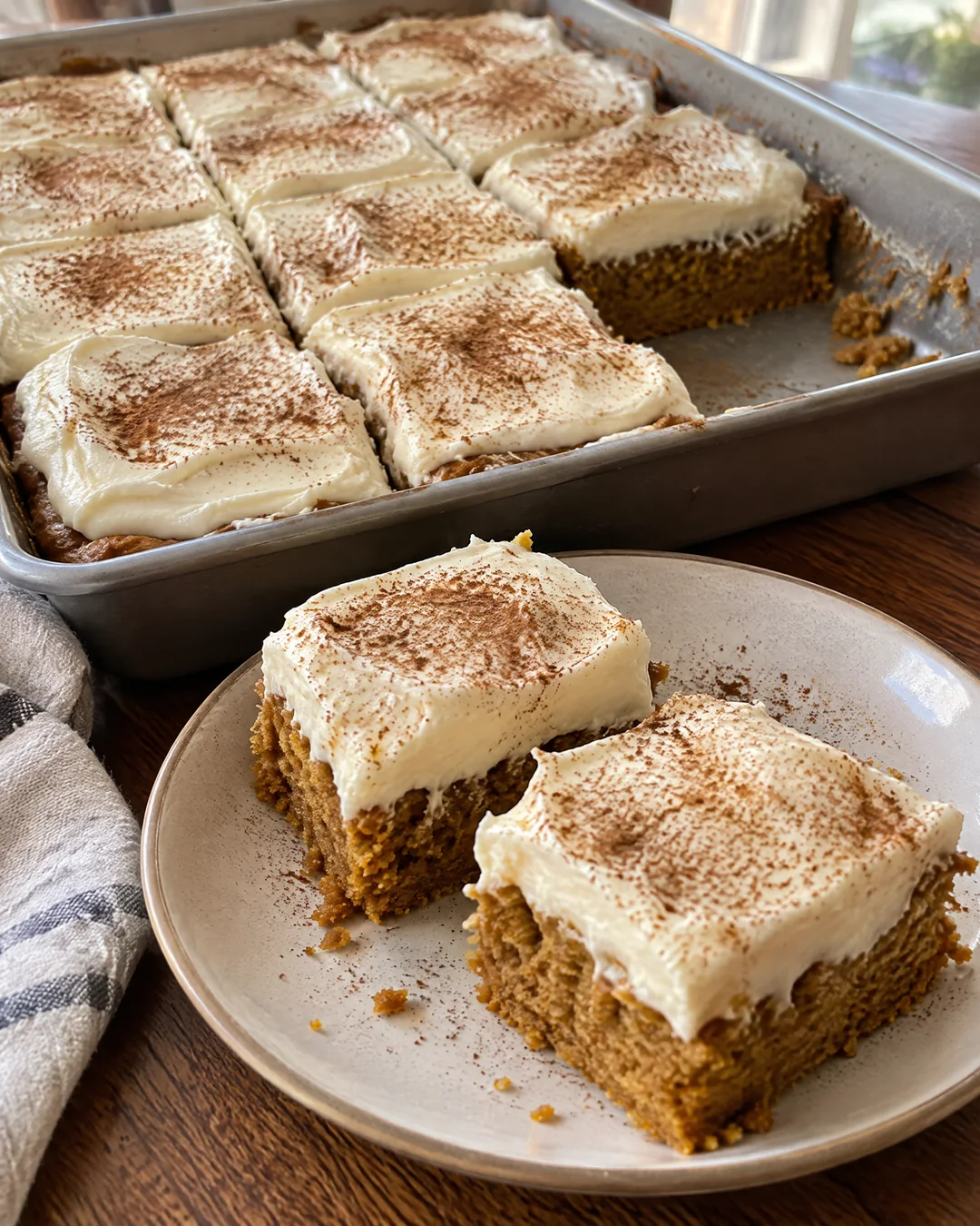 Pumpkin bars with thick cream cheese frosting cut into squares in the pan