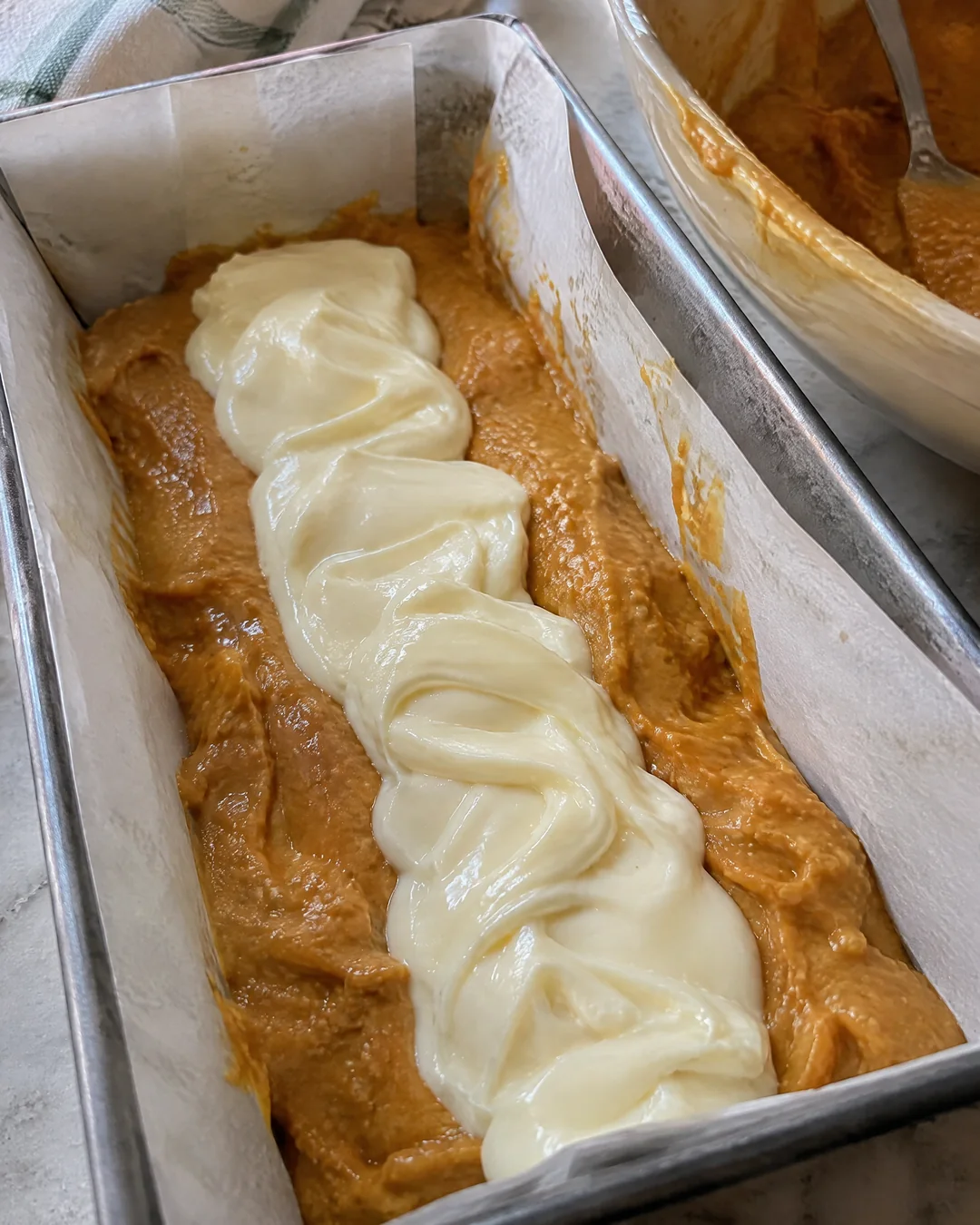 Cream cheese filling spooned down the center of pumpkin bread batter in a loaf pan