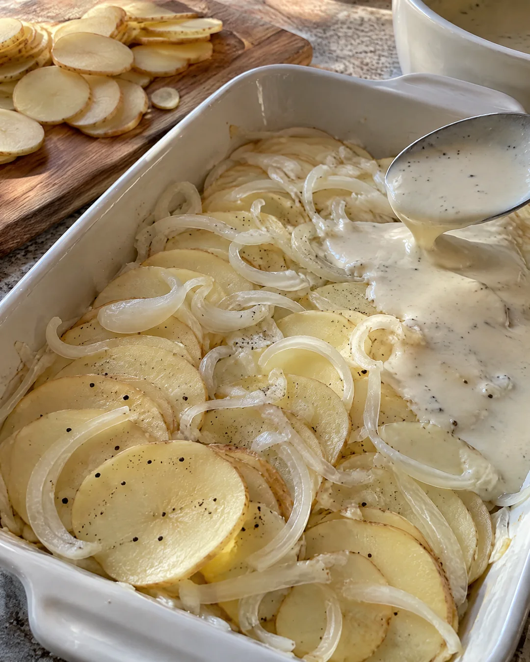 Thin potato slices layered with onion in a baking dish