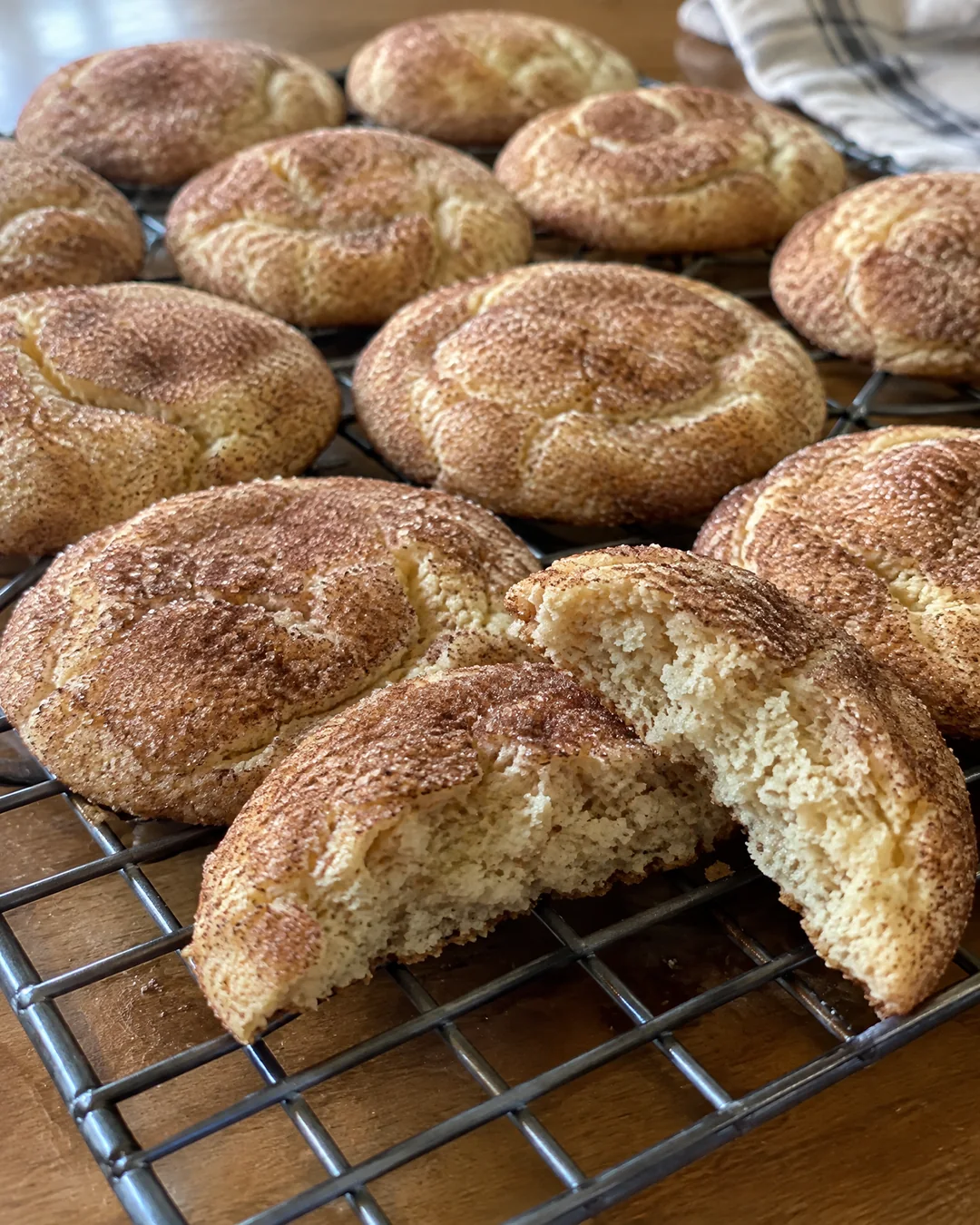Baked snickerdoodles with crackled cinnamon-sugar tops on a cooling rack